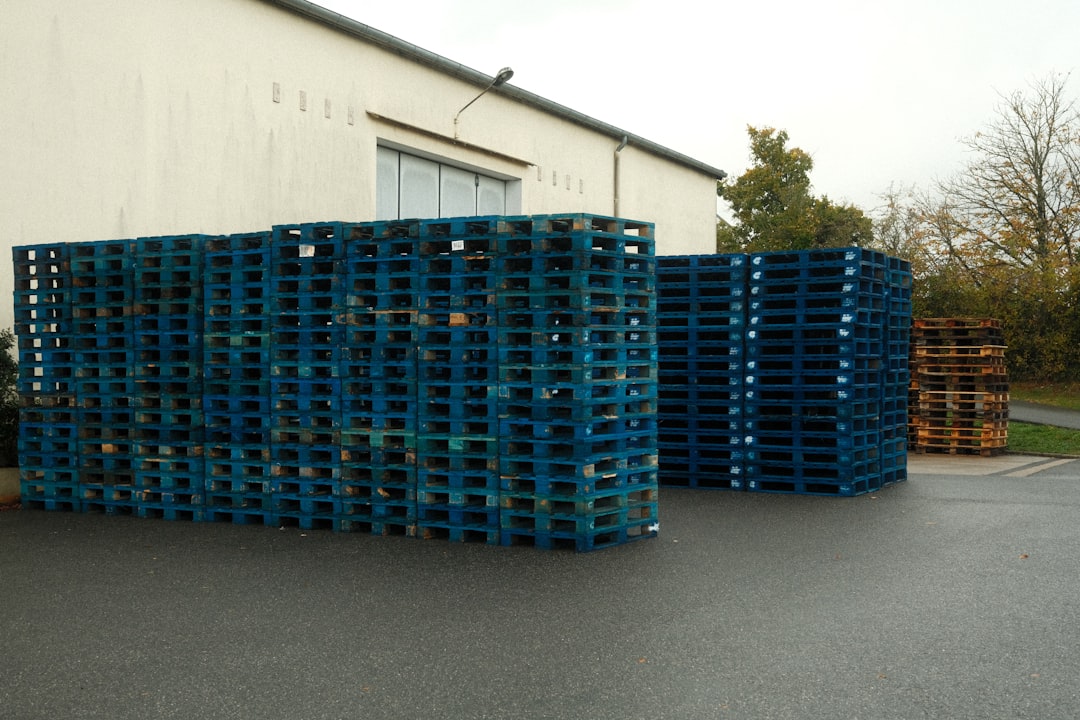 Pallets de plástico azuis empilhados em área externa de armazém